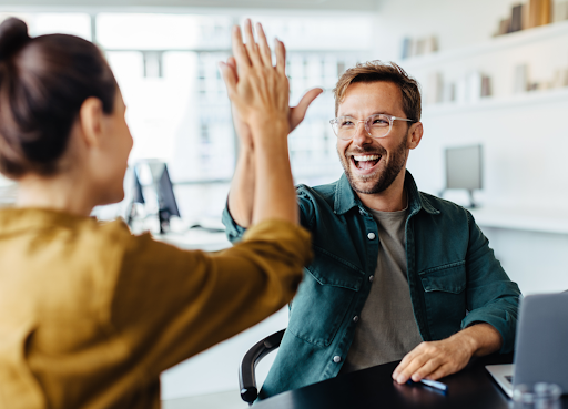 Två kollegor gör high five på kontoret